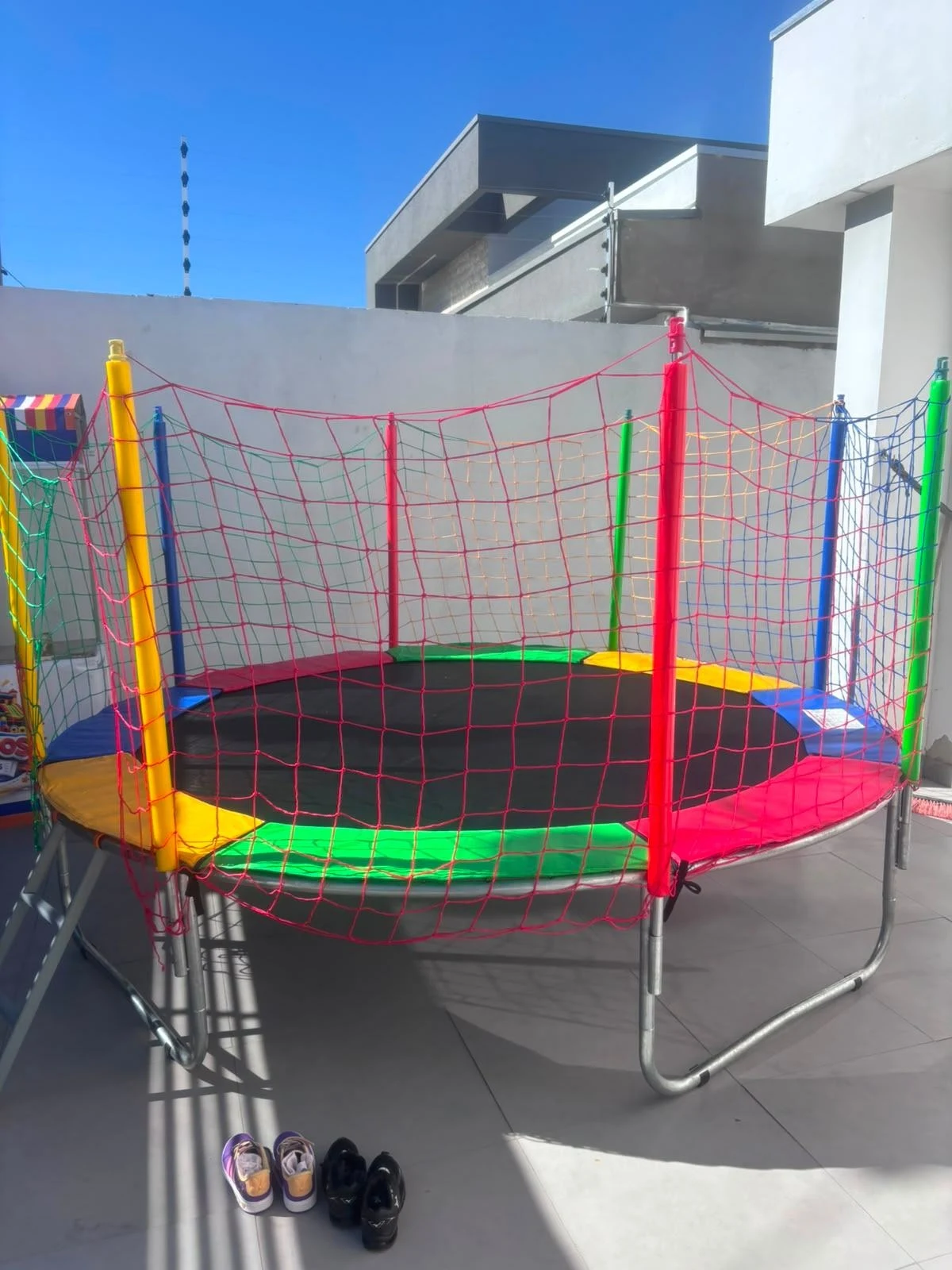 Cama elástica com rede de proteção e bordas coloridas